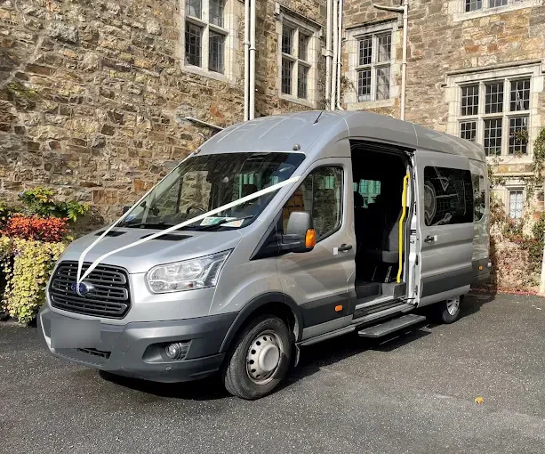 A silver minibus dressed with white wedding ribbons outside Cloughjordan House, a stone country house in North Tipperary